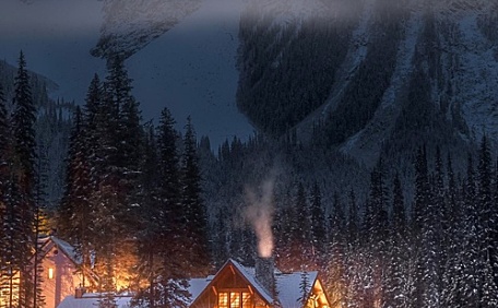 夜晚河边温暖的小屋和远处的雪山壁纸