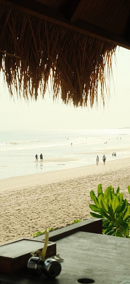 海边稻草棚下沙滩海水海面阴天风景壁纸