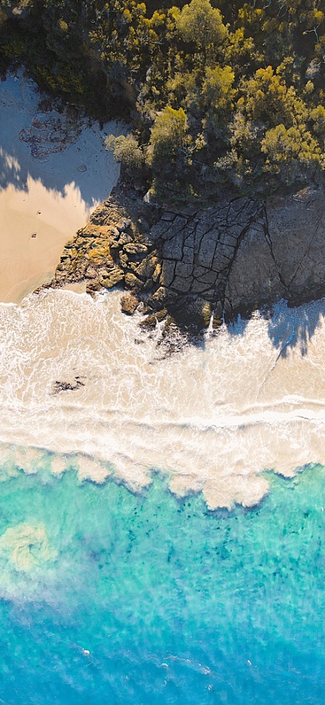 岩石边的白色沙滩和蓝色海面森林风景壁纸